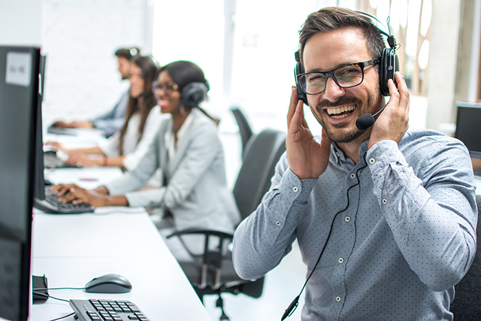 smiling man with a headset sitting in an open office