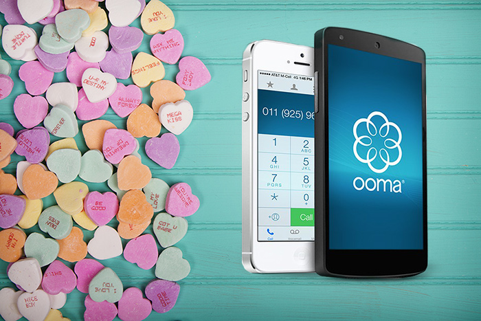 Candy conversation hearts sit next to 2 smartphones with Ooma's calling app