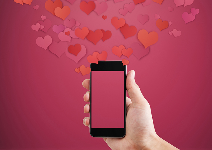 hand holding a mobile phone underneath many hearts