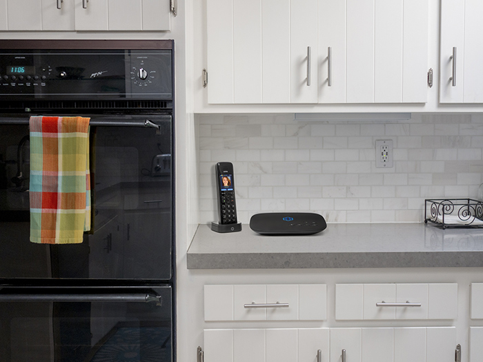 Handset phone and Ooma Telo base station sitting on a kitchen counter
