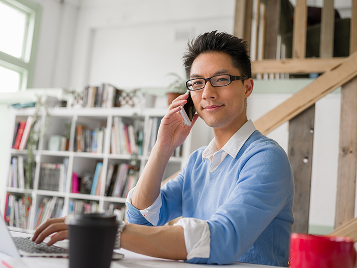 man sitting at a desk and holding a phone to his ear