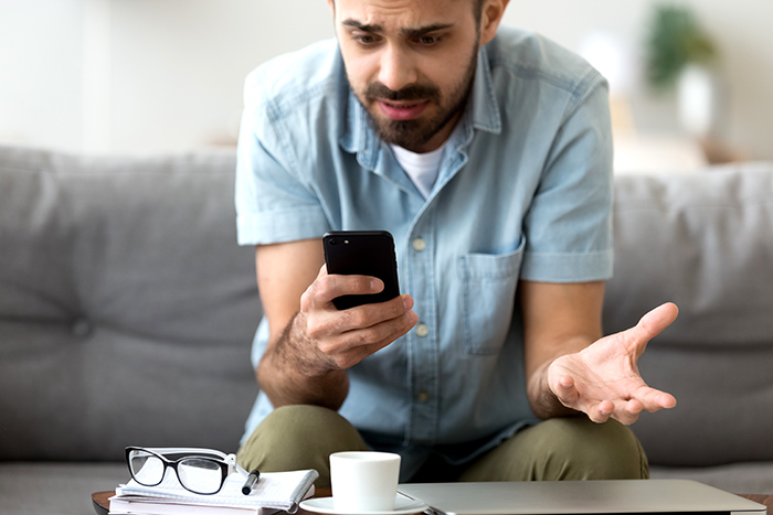 frustrated man using a cell phone while sitting on a couch