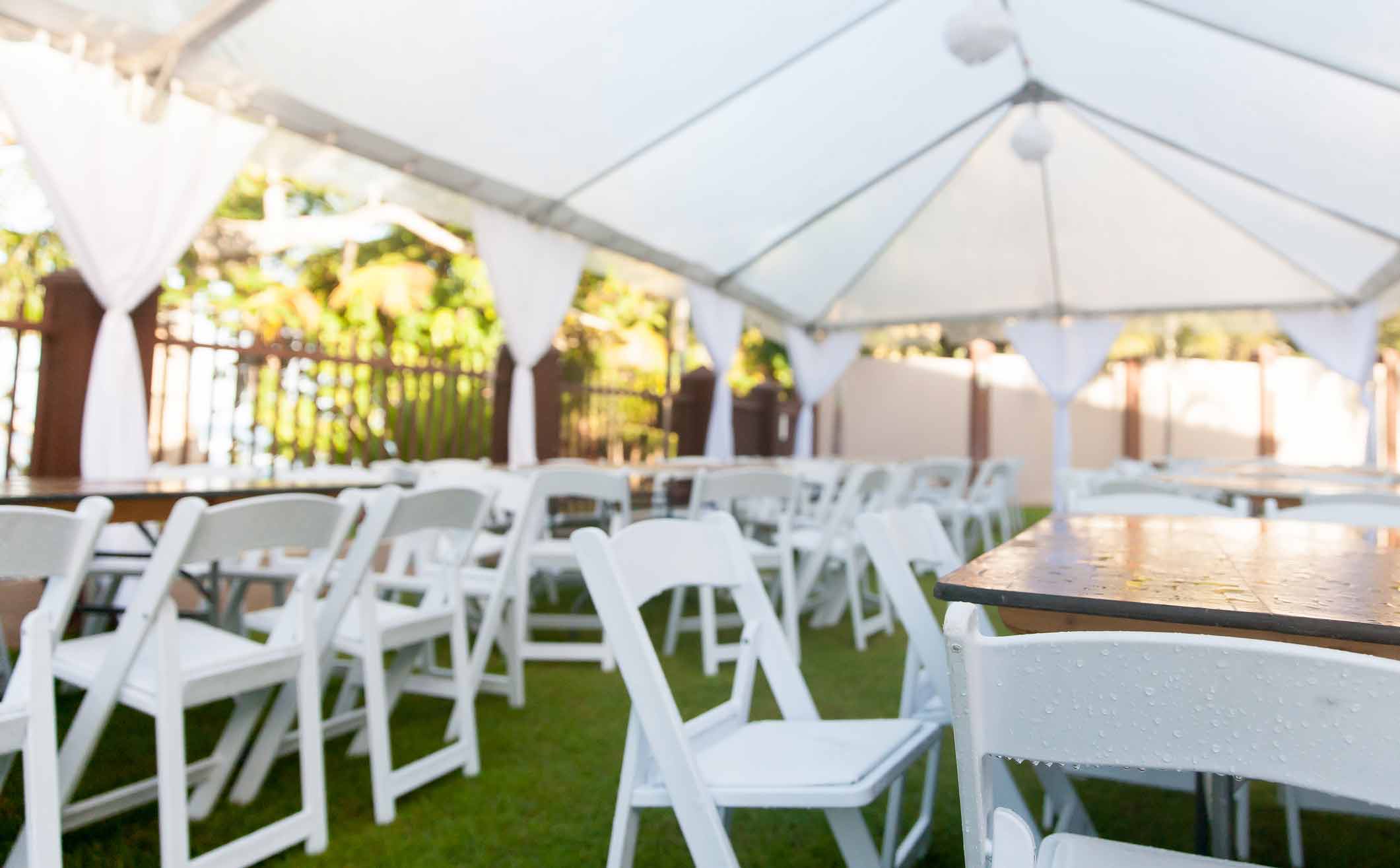 Folding tables and chairs set up under a tent for an outdoor event